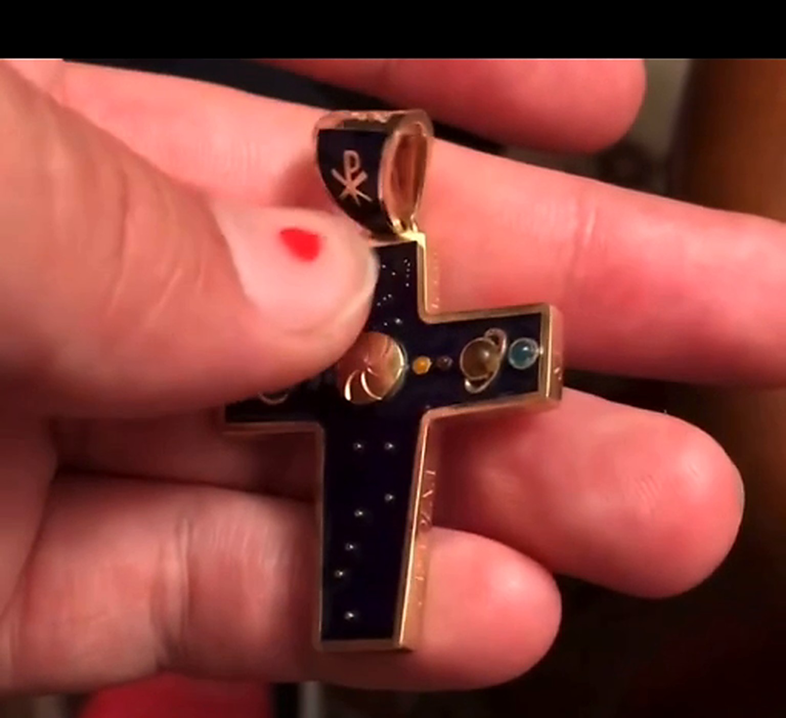 Cross held in hand, blue face